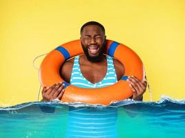 Man with lifebelt is scared to swim. yellow background photo