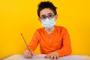 Child at school with face mask for covid-19 coronavirus. yellow background photo