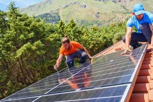 Workers assemble energy system with solar panel for electricity and hot water photo