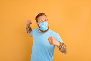 Angry man with beard, tattoo and mask for covid-19 wants to fight photo