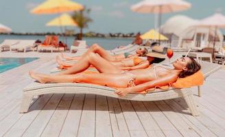 Group of friends in swimsuit drink a cocktail in a swimming pool photo