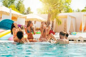 Group of friends in swimsuit enjoy in a swimming pool photo