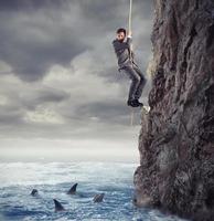 Businessman is likely to fall into the sea with sharks. concept of problems and difficulty in business photo