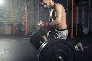 atlético hombre trabajos fuera a el gimnasio con un barra con pesas foto