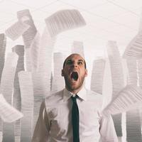 Businessman stressed and overworked screaming in office with flying paper sheets photo