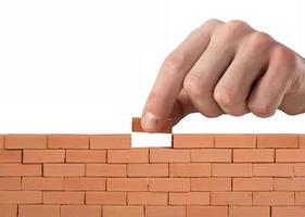 Businessman puts a brick to build a wall. Concept of new business, partnership, integration and startup photo