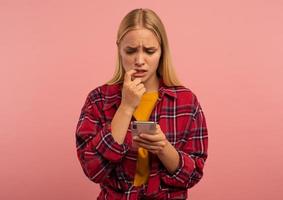 Girl with her smartphone. scared and afraid expression. Pink background photo