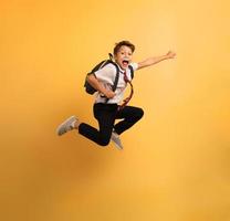 Young boy student jumps high like a super hero. Yellow background photo