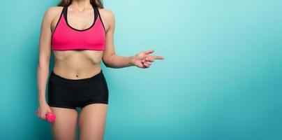 Gymnastic girl indicates something. concept of health and physical fitness . Cyan background photo