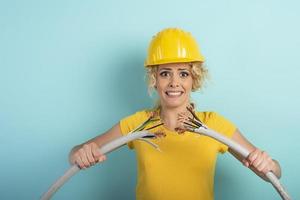 Worker woman with hat breaks an electric cable. Cyan background photo