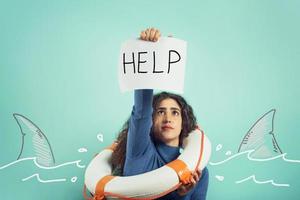 Woman is drowing and ask help with a message of a paper sheet. Cyan background photo