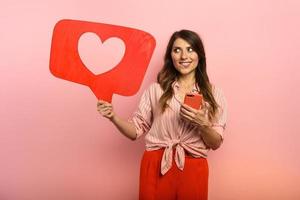 Woman is happy because receives hearts on social network. Pink background photo