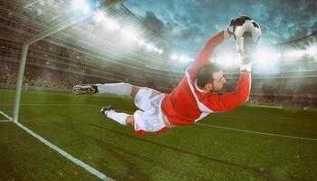 Goalkeeper catches the ball in the stadium during a football game photo