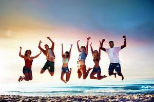 Happy smiling friends jumping at the beach photo