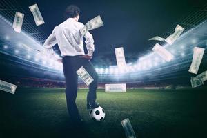 Confident businessman in the center of the soccer field collects a lot of money from the football photo