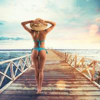 Beautiful blonde girl in swimsuit on a pier photo