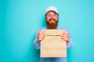 Deliveryman with happy expression is ready to deliver a food package photo