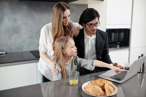 Happy little girl watching a movie on the computer with her father and mother photo