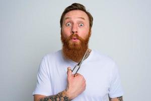 Wondered man with scissors is ready to cut the beard photo