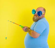 Fat man with beard and sunglasses is unhappy with the fishing rod photo