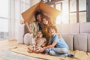 Happy family play together under a cardboard roof photo