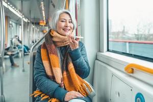 Senior woman send message with a mobile phone in a train photo