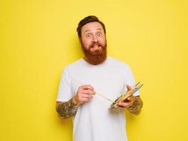 Doubter man with beard and tattoo is ready to draw with brushes photo