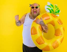 Fat happy man with wig in head is ready to swim with a donut lifesaver photo