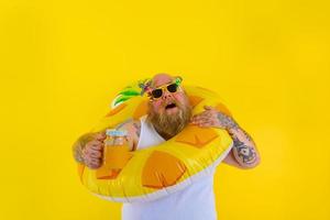 Fat annoyed man with wig in head is ready to swim with a donut lifesaver photo