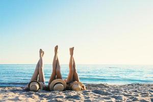 grupo de contento amigos teniendo divertido a Oceano playa con piernas arriba foto