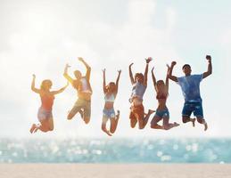 Happy smiling friends jumping at the beach photo