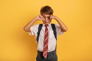 Child cries because does not want to go to school. Yellow background photo