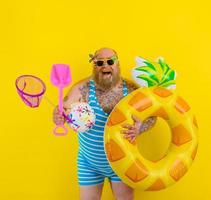 Fat happy man with wig in head is ready to swim with a donut lifesaver photo