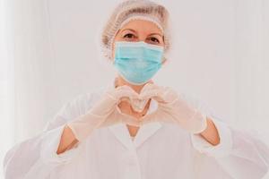 Doctor with mask makes a heart with her hands photo