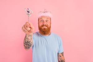 Happy man with beard and tattoos acts like a princess of a tale photo