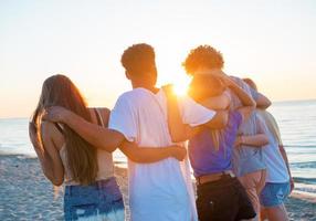 Group of happy friends having fun at ocean beach photo