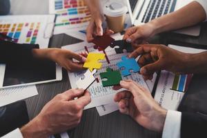 Businessmen building colored puzzles together. Concept of teamwork, partnership, integration and startup photo