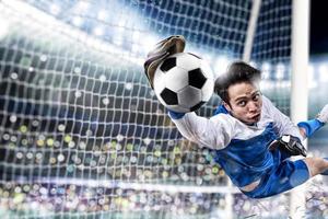 Goalkeeper catches the ball in the stadium during a football game. photo