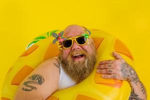 Fat happy man with wig in head is ready to swim with a donut lifesaver photo