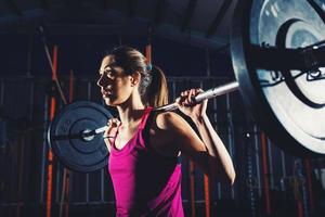 Athletic girl works out at the gym with a barbell photo
