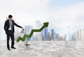 Businessman that watering a plant with a shape of arrow. Concept of growing of company economy . photo