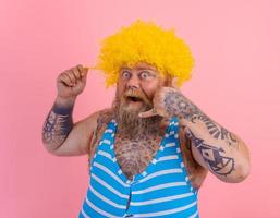 Amazed man with yellow wig and swimsuit is ready to the summer photo