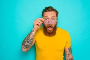 Man with yellow t-shirt and beard is shocked about something photo