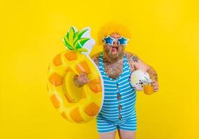 Fat happy man with wig in head is ready to swim with a donut lifesaver photo