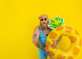 Fat amazed man with wig in head is ready to swim with a donut lifesaver photo