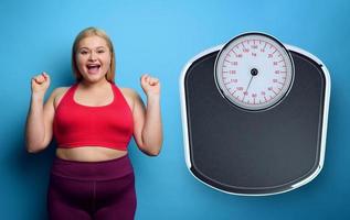 Fat girl does gym at home with satisfied expression because she decrease her weight. purple background photo