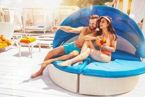 Couple in swimsuit drink a cocktail in a beach place photo