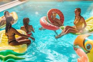 Group of friends in swimsuit enjoy in a swimming pool photo