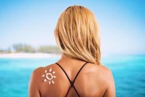 Girl in swimsuit with a sun made with sunscreen photo