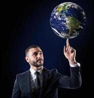 Businessman holds the world with a finger. World provided by NASA photo